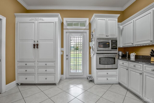 kitchen with ornamental molding, appliances with stainless steel finishes, dark stone countertops, and white cabinets