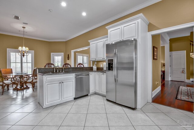 kitchen with white cabinetry, stainless steel appliances, kitchen peninsula, and light tile patterned floors