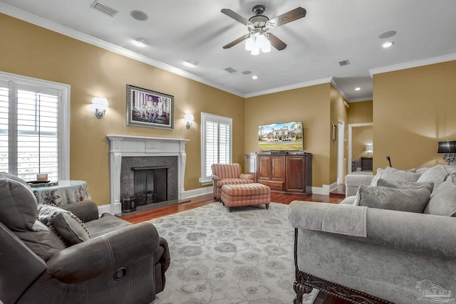 living room featuring wood-type flooring, ornamental molding, and ceiling fan