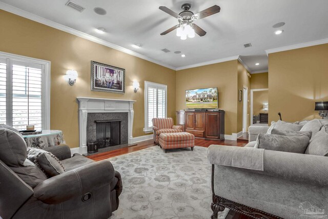 living room featuring wood-type flooring, ornamental molding, and ceiling fan