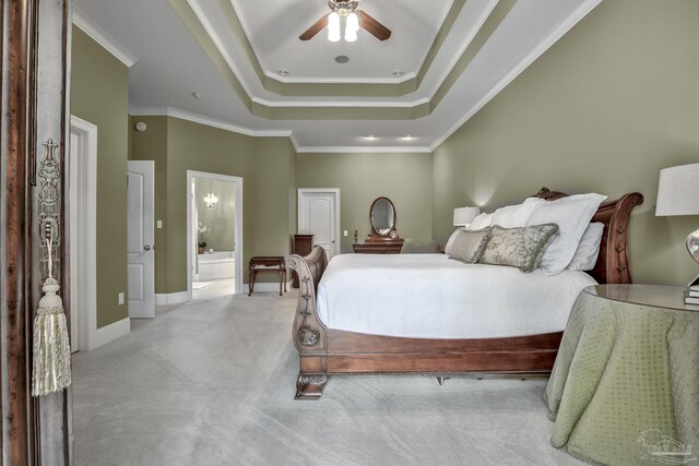 bedroom featuring ensuite bathroom, ornamental molding, ceiling fan, a tray ceiling, and light carpet