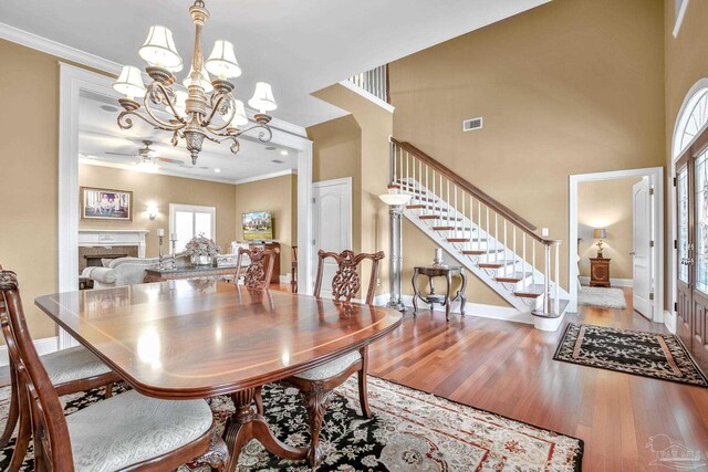 dining area with hardwood / wood-style floors, a notable chandelier, a high end fireplace, and ornamental molding