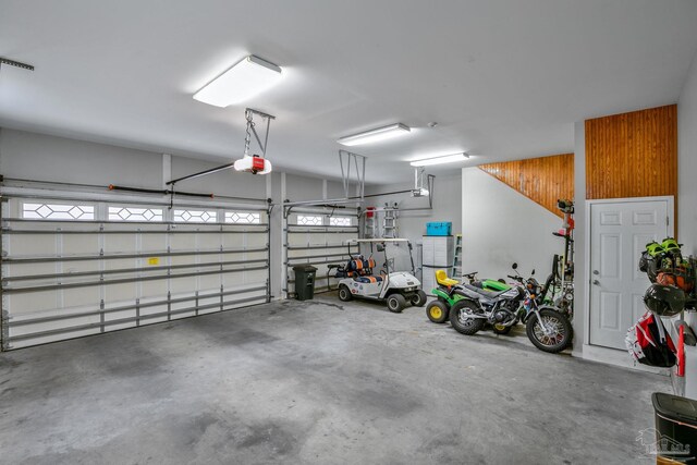 garage with a garage door opener and wooden walls