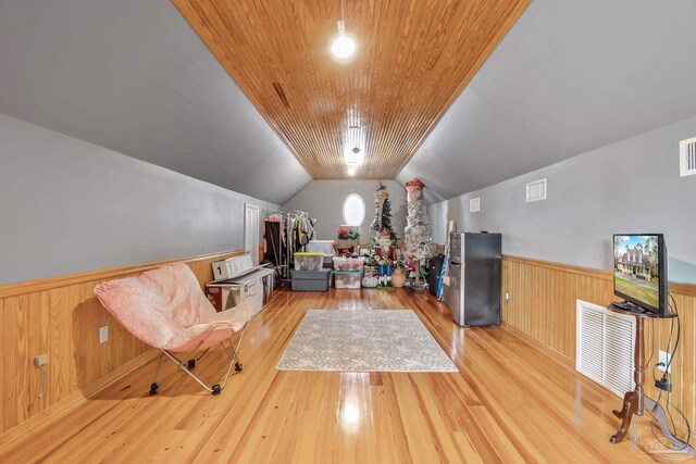 interior space with wood ceiling, vaulted ceiling, light hardwood / wood-style flooring, and wood walls