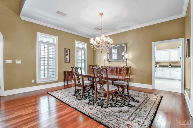 dining area with ornamental molding, hardwood / wood-style floors, and a notable chandelier