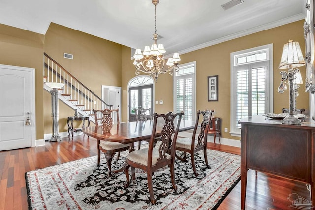 dining area with ornamental molding, dark wood-type flooring, a notable chandelier, and french doors