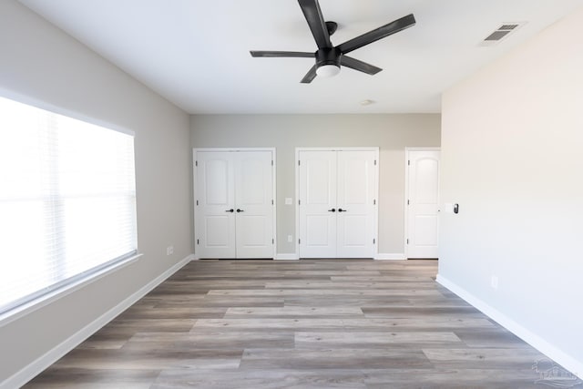 9901 Raymar St Unit A, Pensacola, FL 32534 - unfurnished bedroom with visible vents, baseboards, two closets, and wood finished floors