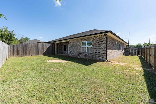 9901 Raymar St Unit A, Pensacola, FL 32534 - back of house with central AC, a lawn, a fenced backyard, and brick siding