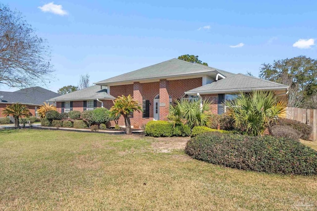 view of front facade featuring brick siding, fence, and a front lawn