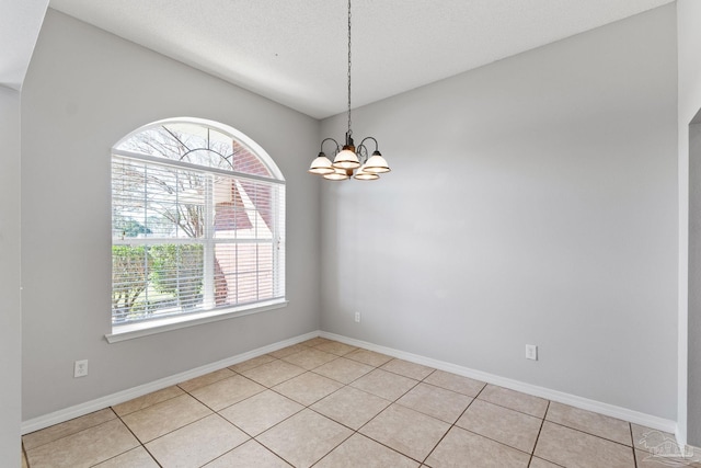 unfurnished room with light tile patterned floors, baseboards, and a notable chandelier