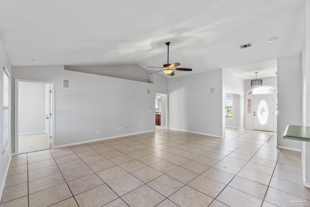 spare room with lofted ceiling, a textured ceiling, light tile patterned flooring, and visible vents