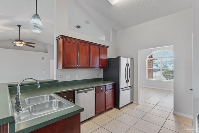 kitchen featuring stainless steel appliances, dark countertops, light tile patterned flooring, vaulted ceiling, and a sink