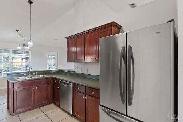 kitchen featuring stainless steel appliances, a sink, visible vents, dark countertops, and pendant lighting