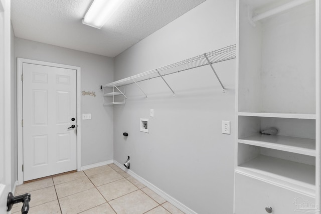 washroom with light tile patterned floors, a textured ceiling, hookup for a washing machine, laundry area, and electric dryer hookup