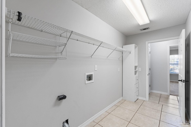 washroom featuring a textured ceiling, light tile patterned flooring, laundry area, washer hookup, and visible vents