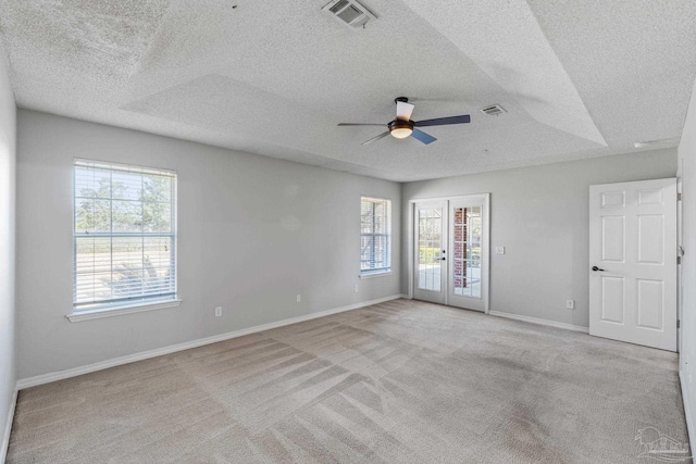 unfurnished room featuring french doors, visible vents, light carpet, and a healthy amount of sunlight