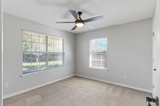 empty room with light carpet, ceiling fan, baseboards, and a textured ceiling