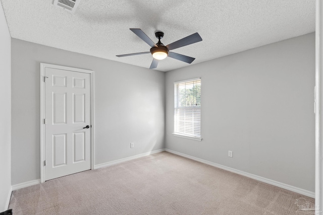 empty room featuring light carpet, a ceiling fan, visible vents, and baseboards