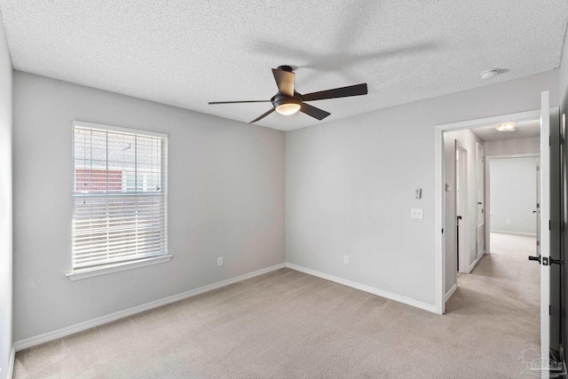 empty room featuring light carpet, ceiling fan, baseboards, and a textured ceiling