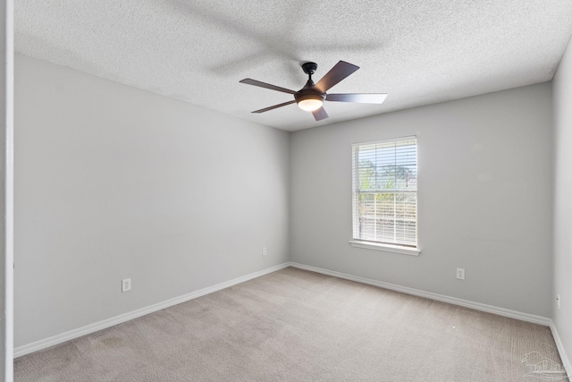 spare room featuring light carpet, a textured ceiling, baseboards, and a ceiling fan