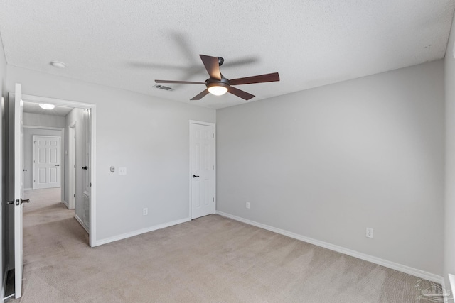 unfurnished bedroom with visible vents, light colored carpet, a ceiling fan, a textured ceiling, and baseboards