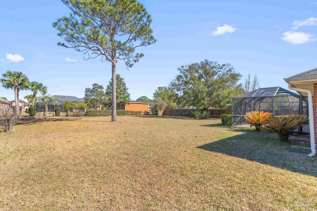 view of yard with glass enclosure and fence