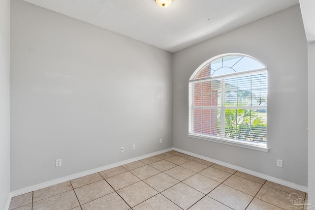 unfurnished room featuring baseboards and light tile patterned flooring