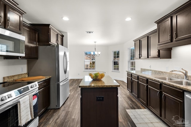 kitchen with visible vents, a kitchen island, stainless steel appliances, dark brown cabinets, and a sink