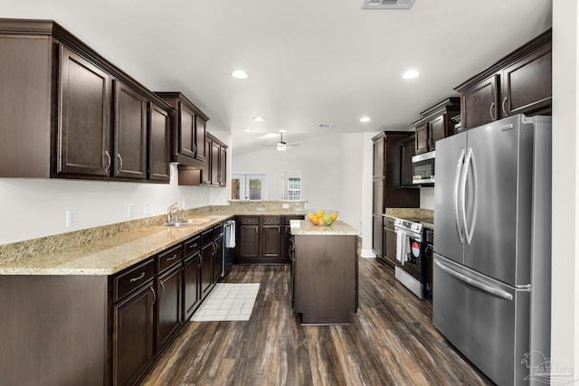 kitchen featuring dark wood finished floors, appliances with stainless steel finishes, dark brown cabinetry, a sink, and a kitchen island