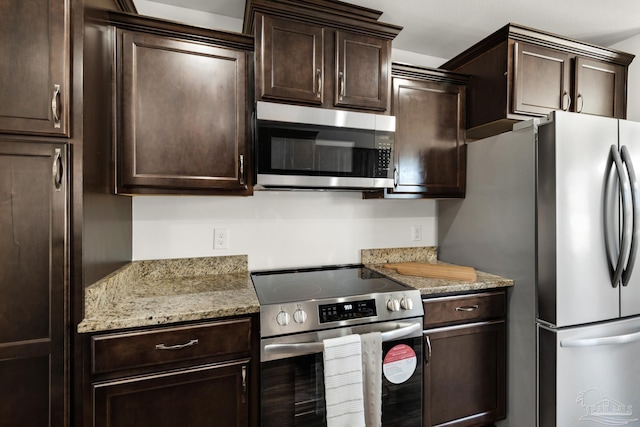 kitchen featuring light stone counters, stainless steel appliances, and dark brown cabinets