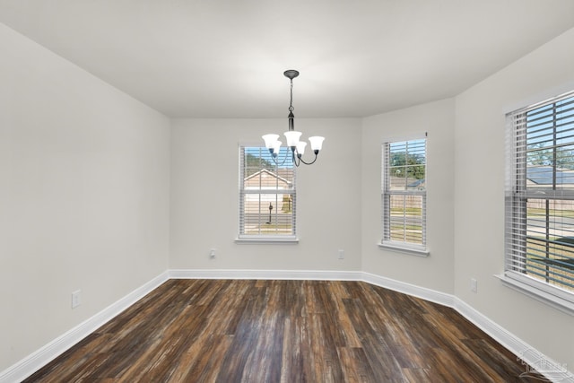 unfurnished dining area with a notable chandelier, dark wood-type flooring, and baseboards