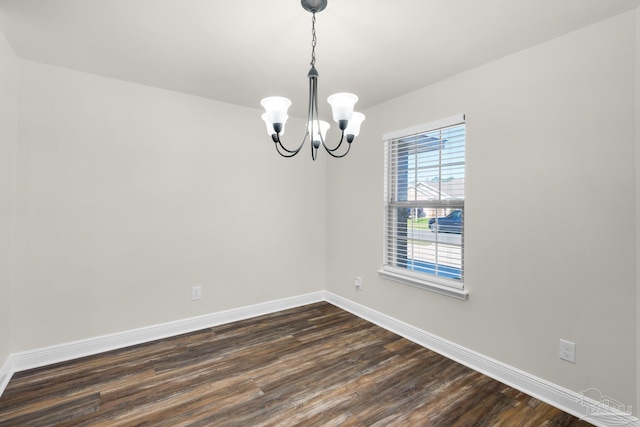 empty room featuring dark wood-style flooring, baseboards, and an inviting chandelier