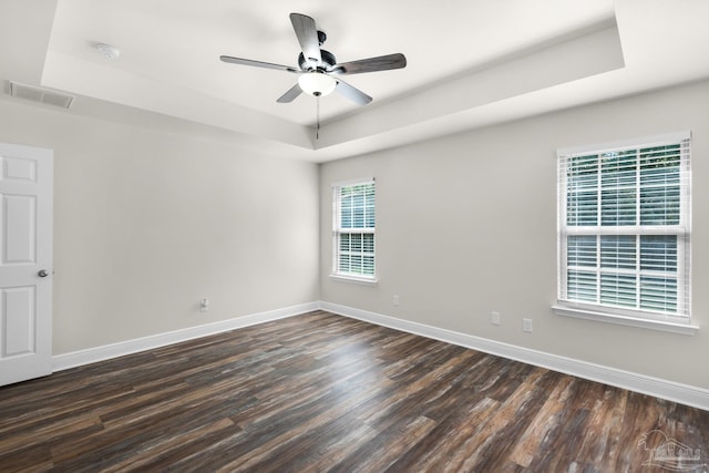 unfurnished room with a raised ceiling, visible vents, and baseboards