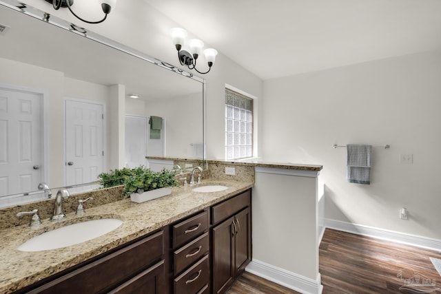 full bathroom with double vanity, a sink, baseboards, and wood finished floors