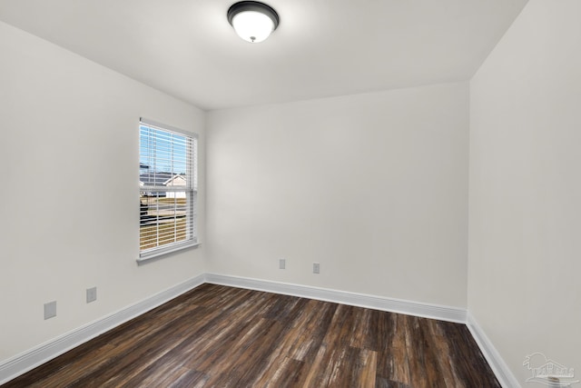 spare room featuring dark wood-style floors and baseboards