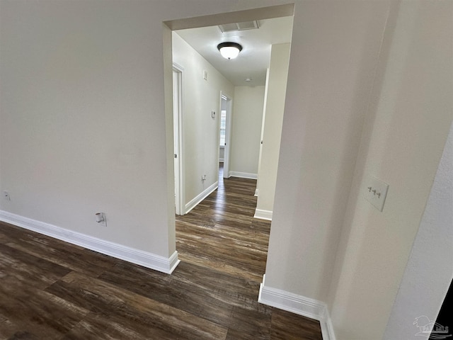 corridor featuring dark wood finished floors, visible vents, and baseboards