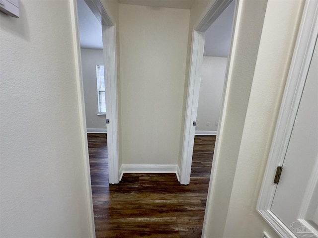 hall featuring dark wood-style flooring and baseboards