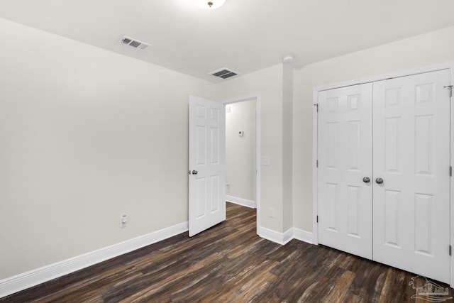 unfurnished bedroom with dark wood-style floors, a closet, visible vents, and baseboards