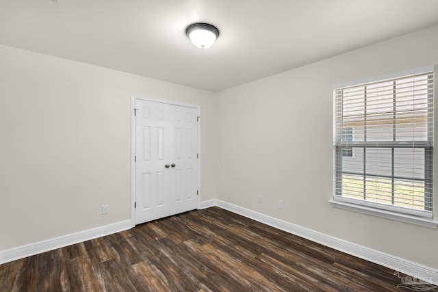 unfurnished room with dark wood finished floors and baseboards