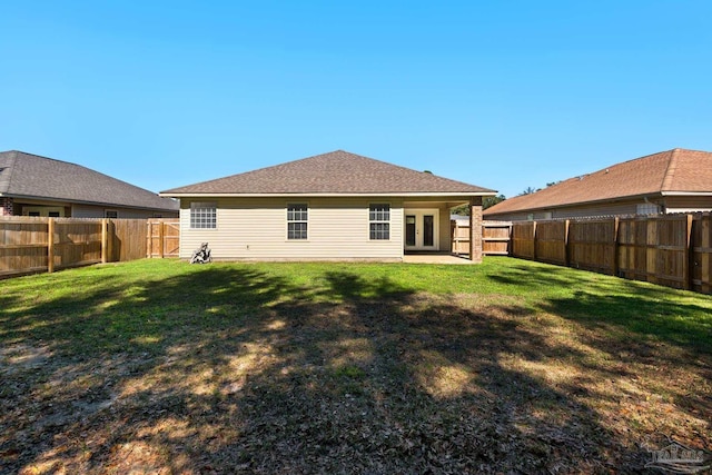 back of house with french doors, a fenced backyard, and a yard