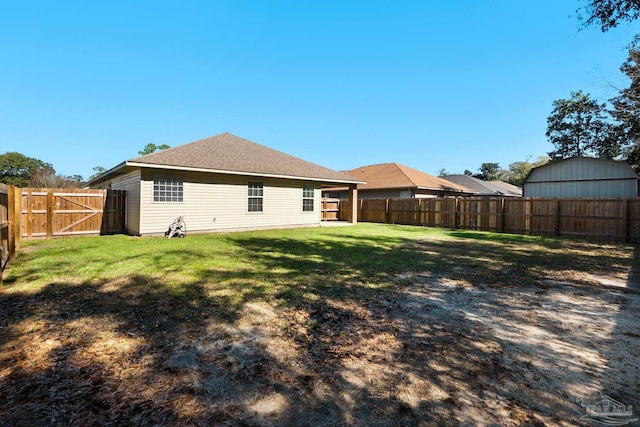 rear view of property featuring a yard and a fenced backyard