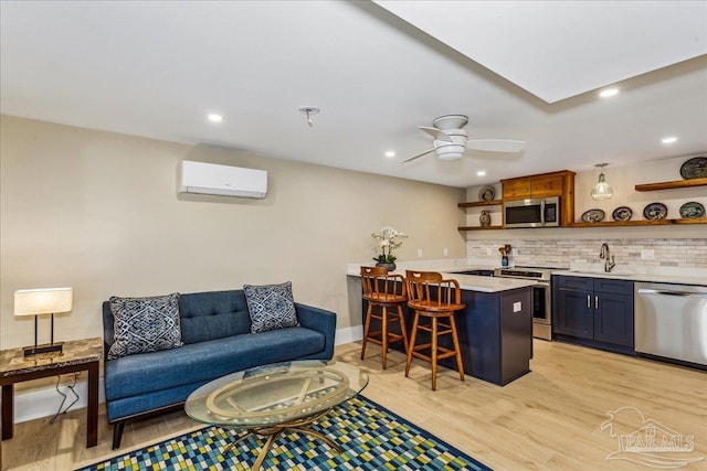 living room with ceiling fan, a wall mounted air conditioner, wet bar, and light hardwood / wood-style floors