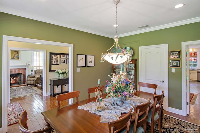 607 Goodwill Cir, Silas, AL 36919 - dining space featuring healthy amount of natural light, baseboards, hardwood / wood-style flooring, a brick fireplace, and crown molding
