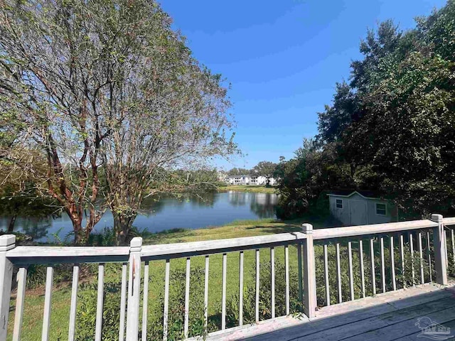 wooden deck with a yard, a water view, and a shed