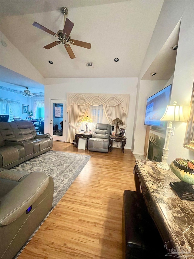 living room featuring hardwood / wood-style floors, ceiling fan, and vaulted ceiling