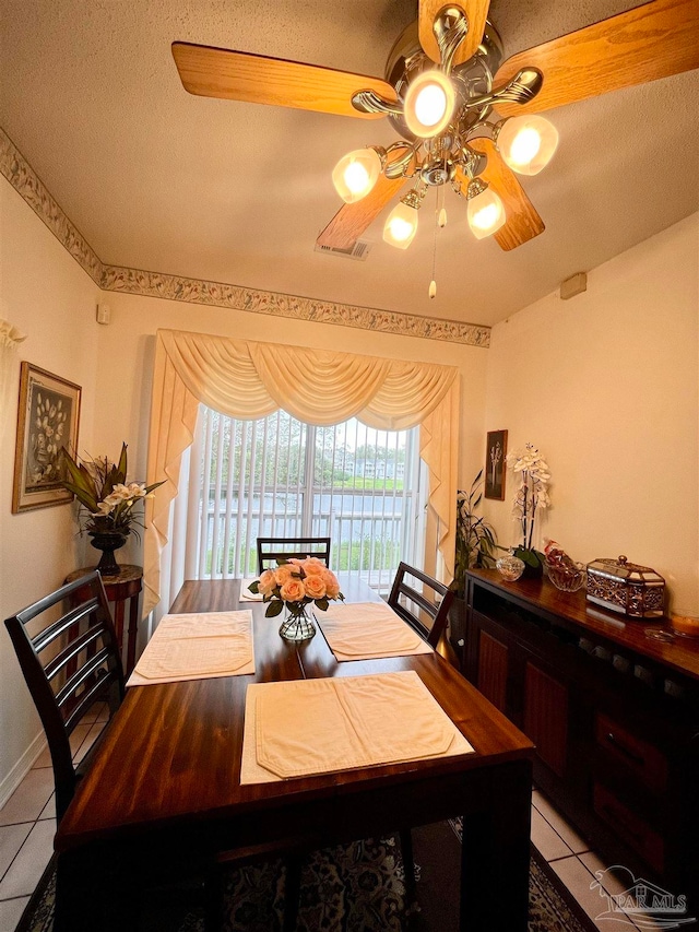 tiled dining space featuring ceiling fan and a textured ceiling