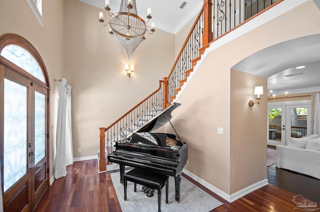 foyer featuring ornamental molding, french doors, dark wood-type flooring, and a towering ceiling