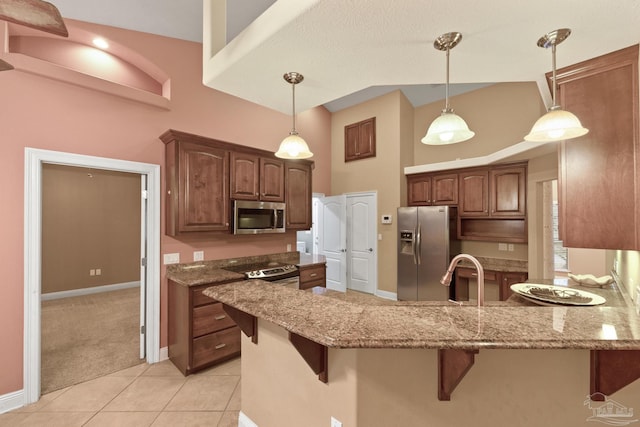 kitchen with light tile patterned floors, kitchen peninsula, appliances with stainless steel finishes, and a kitchen breakfast bar