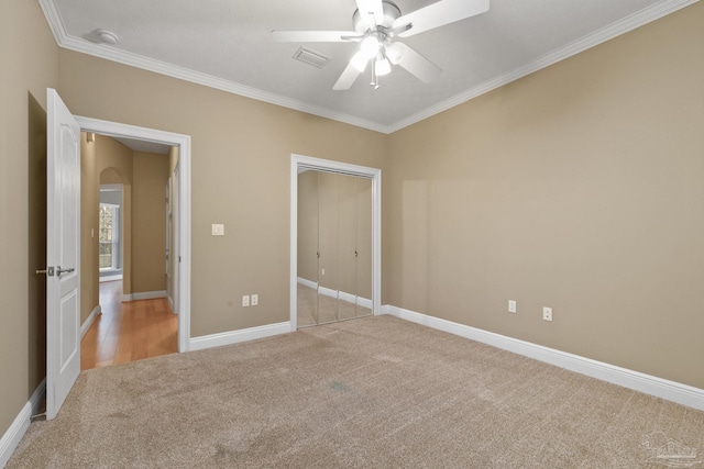 unfurnished bedroom featuring ceiling fan, a closet, light carpet, and ornamental molding