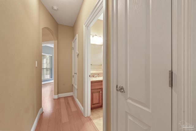 corridor with light hardwood / wood-style floors and sink